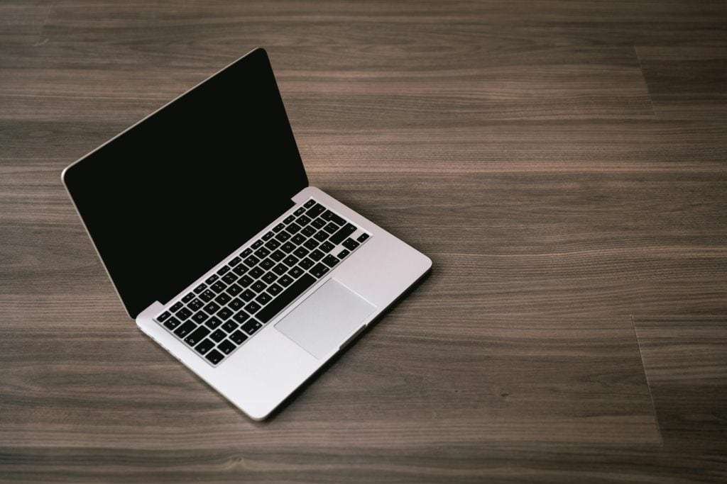 木質書桌上放著一台 Macbook 筆電